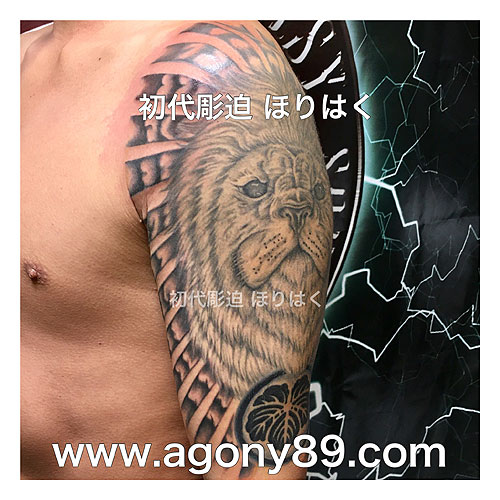 ライオンの顔と家紋に、雲から光差す背景のタトゥー